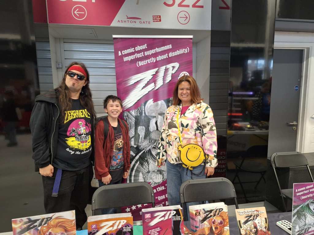 Photo of writer Mike Scrase posing in sunglasses with Zip a young reader and his mother behind our table.